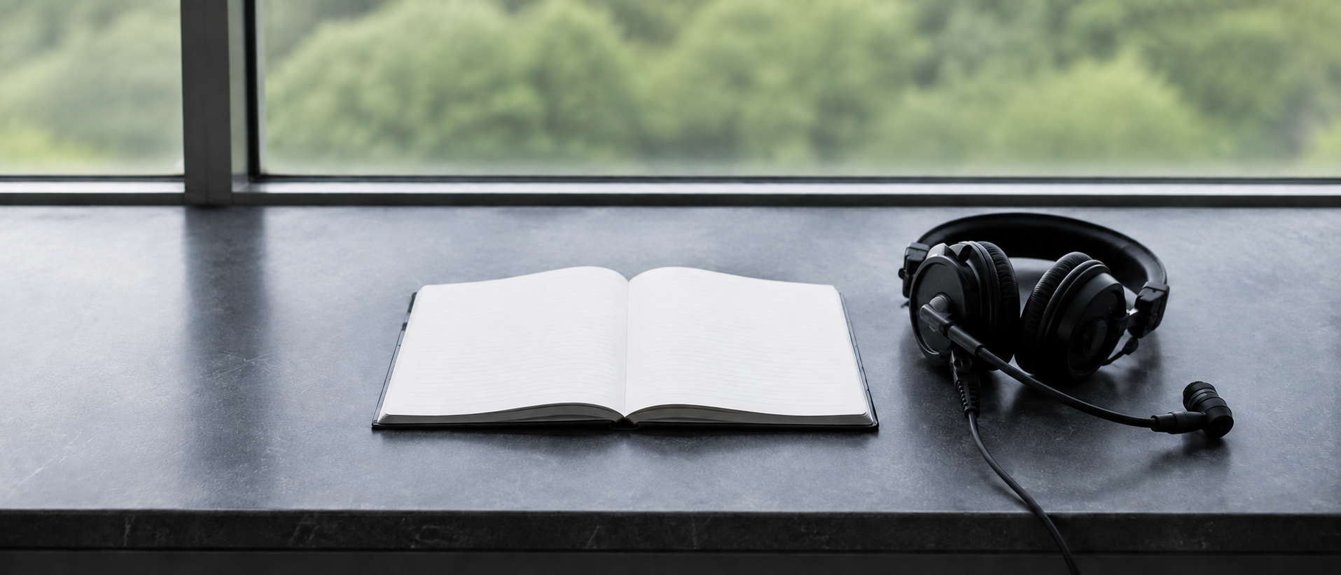 Empty press desk with an open notebook and an unbranded broadcasting headset